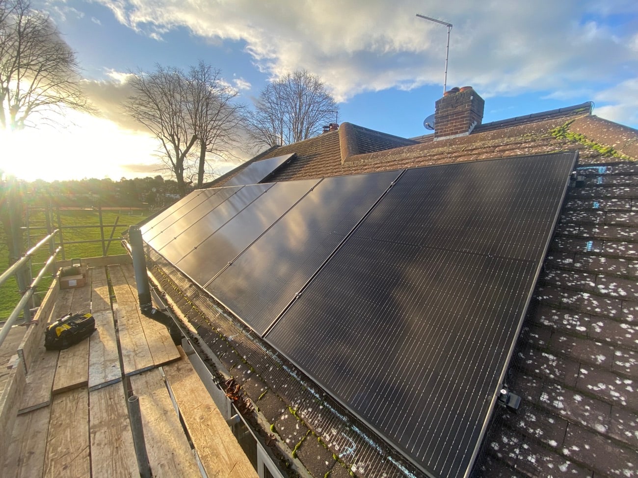 Black solar panels on a tiled house roof at golden hour
