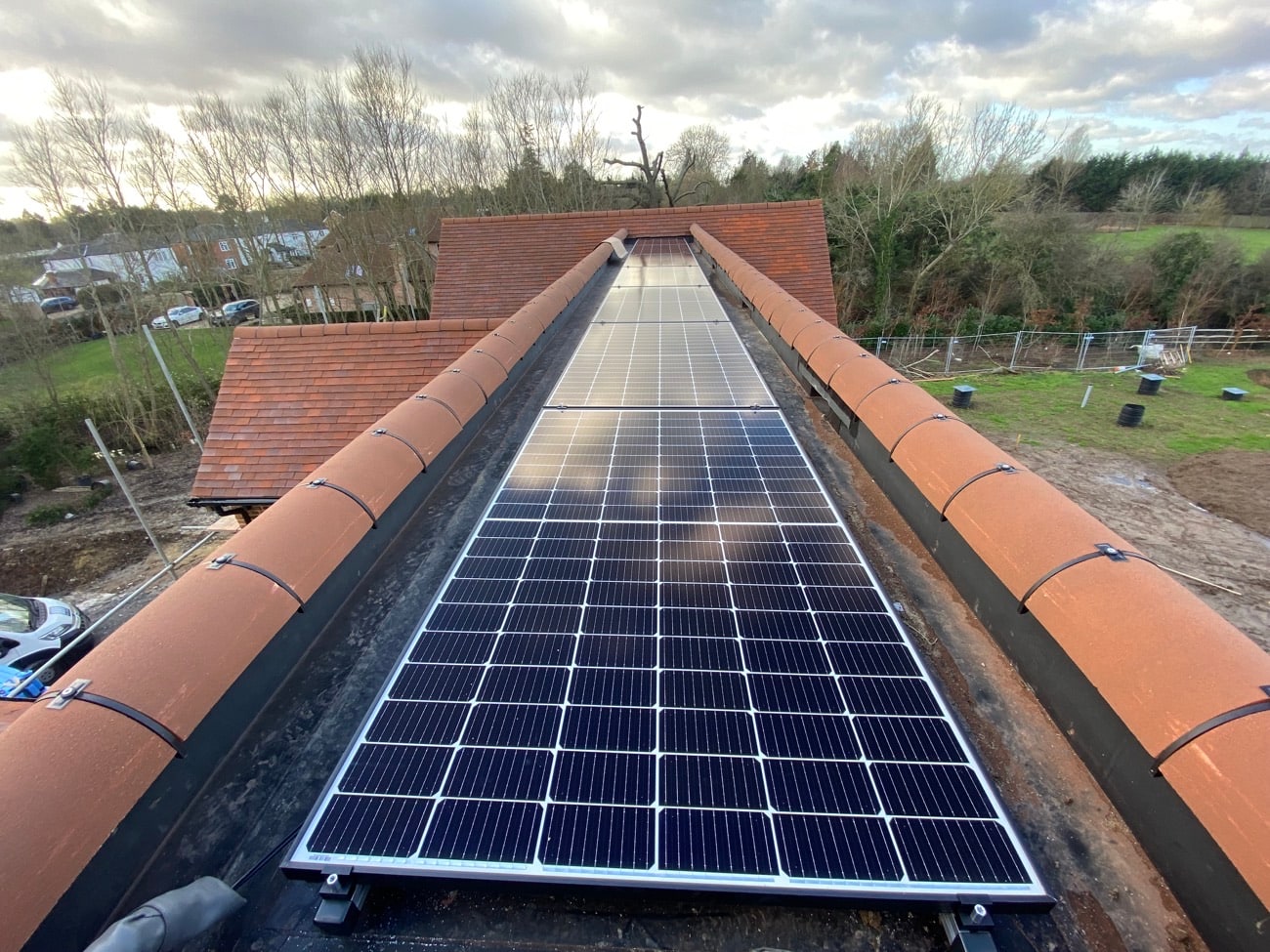 Full-width solar panel array along a red tiled roof