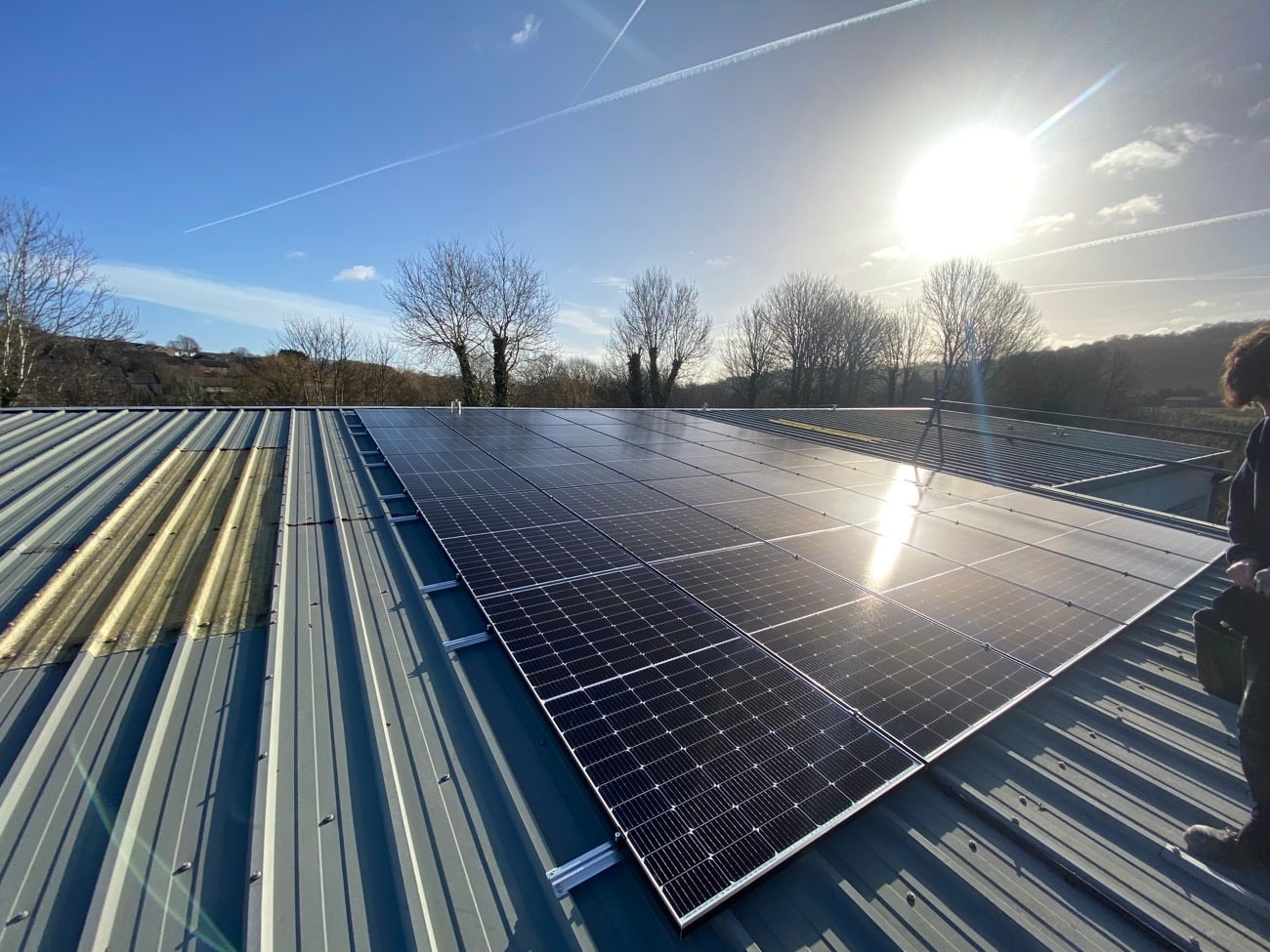 Commercial solar PV array on a metal industrial roof in bright sun
