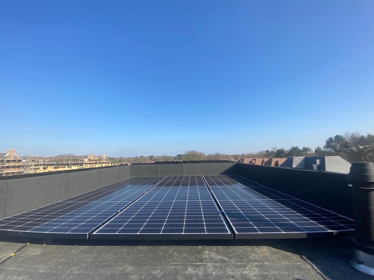 Flat-roof mounted solar panel array against a blue sky