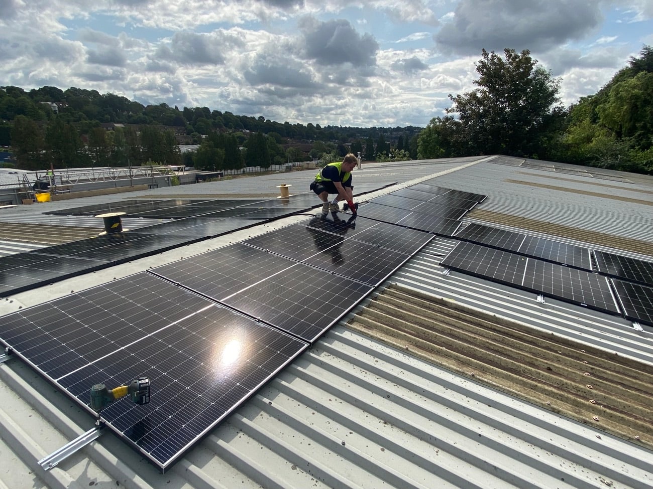 Installer fitting solar panels on a large commercial metal roof
