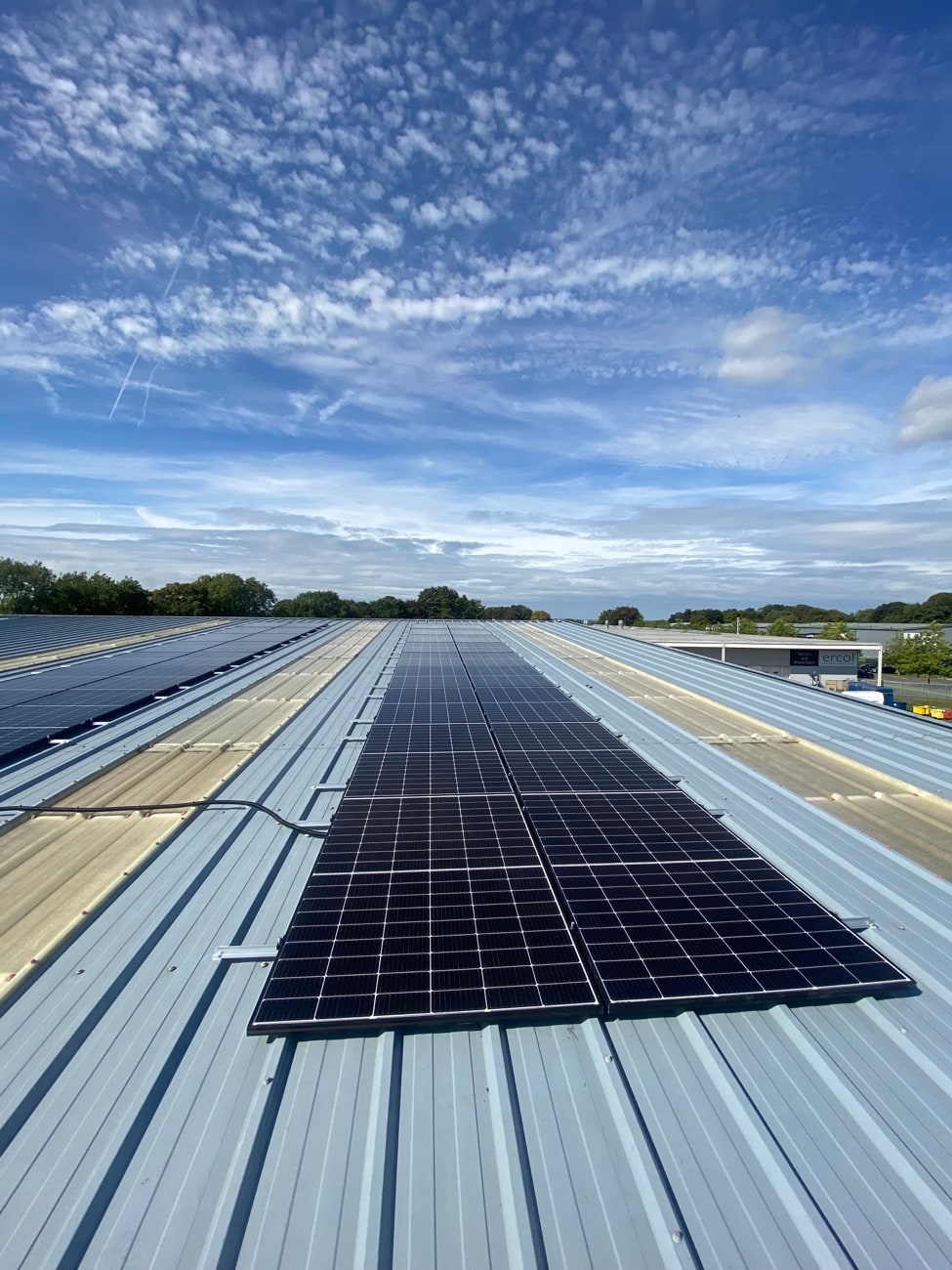 Long commercial solar panel run on an industrial roof against blue sky
