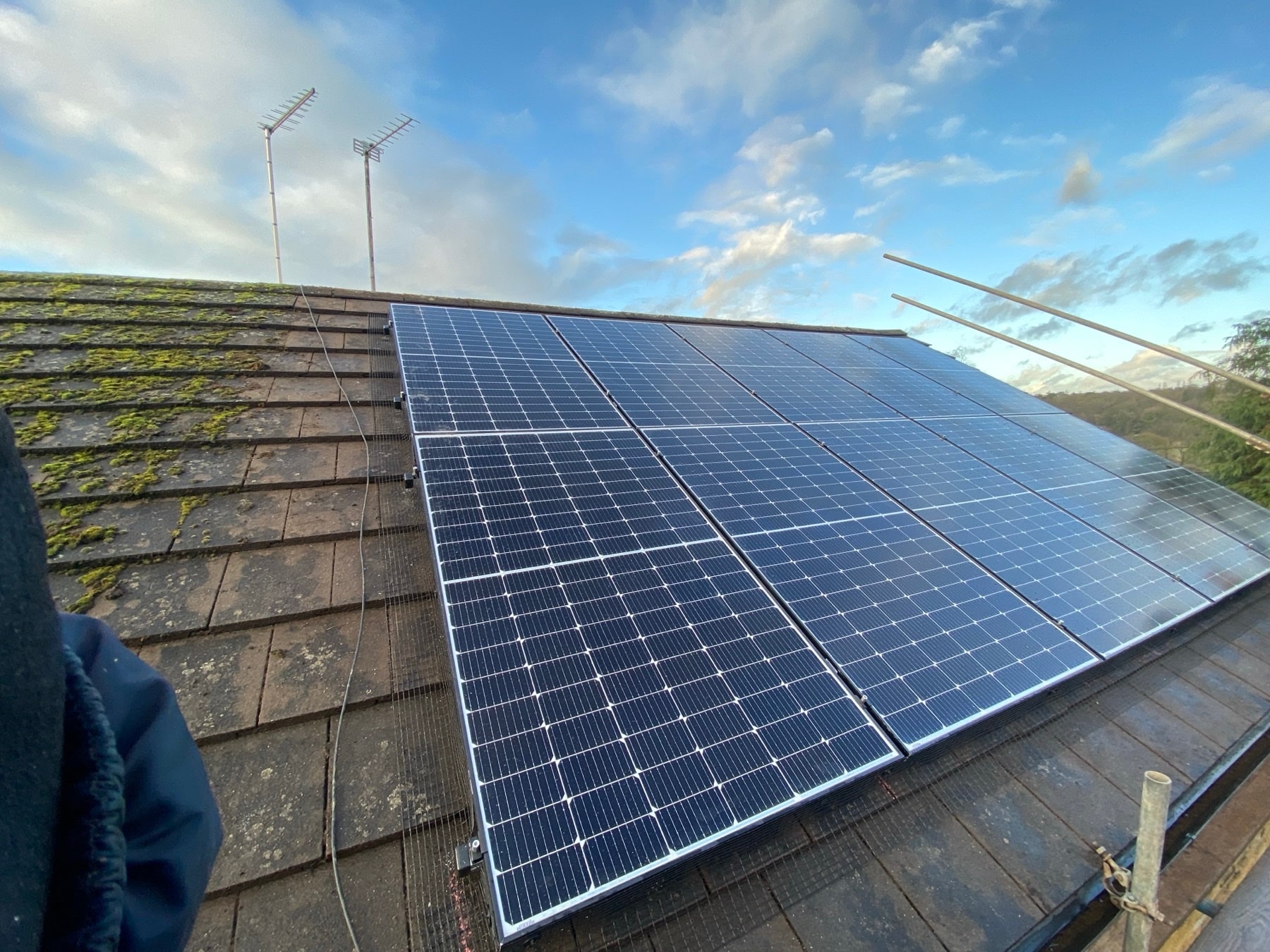 Solar panels on a tiled house roof under a clear blue sky