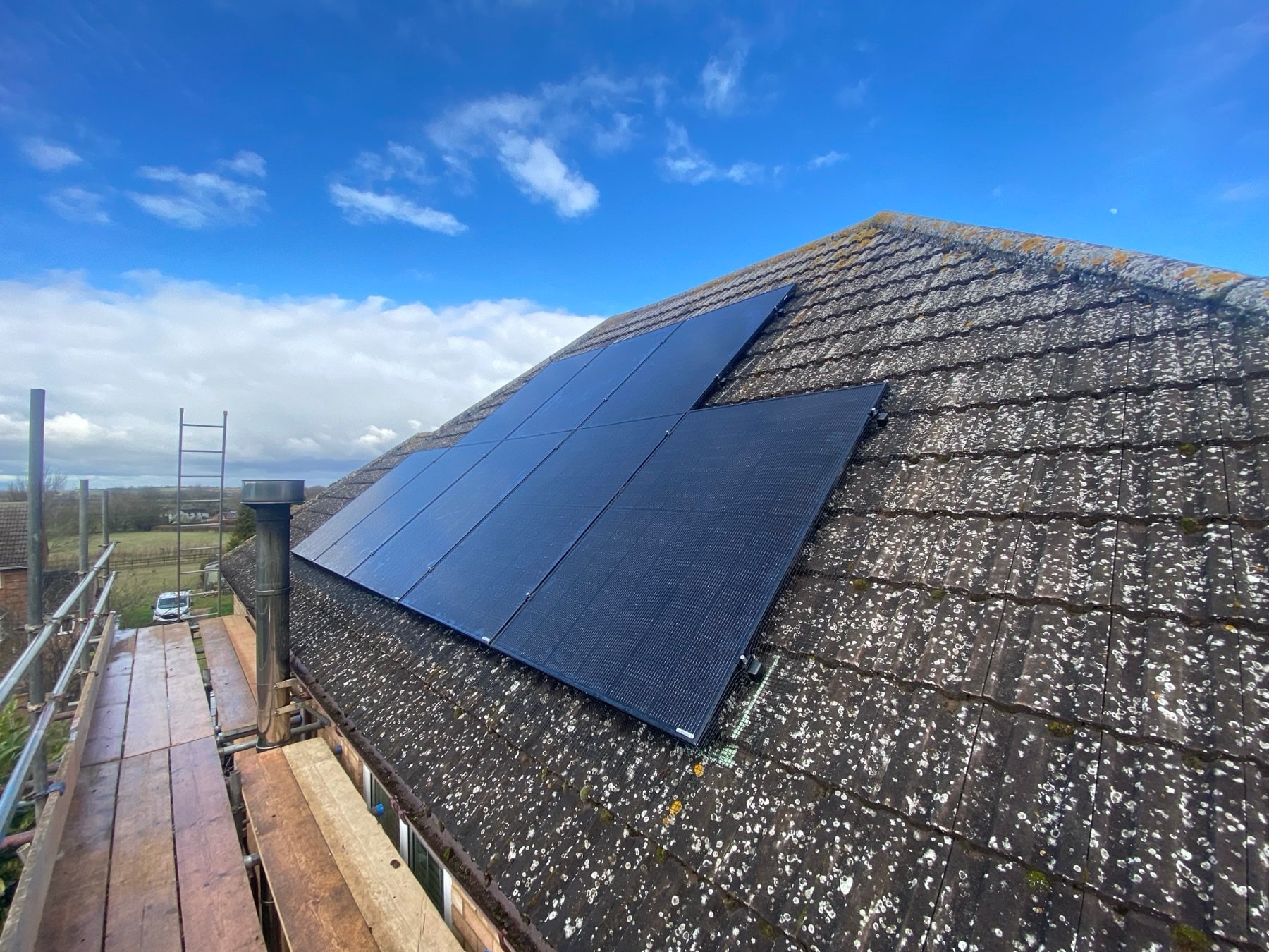 Black solar panels on a tiled roof under blue sky