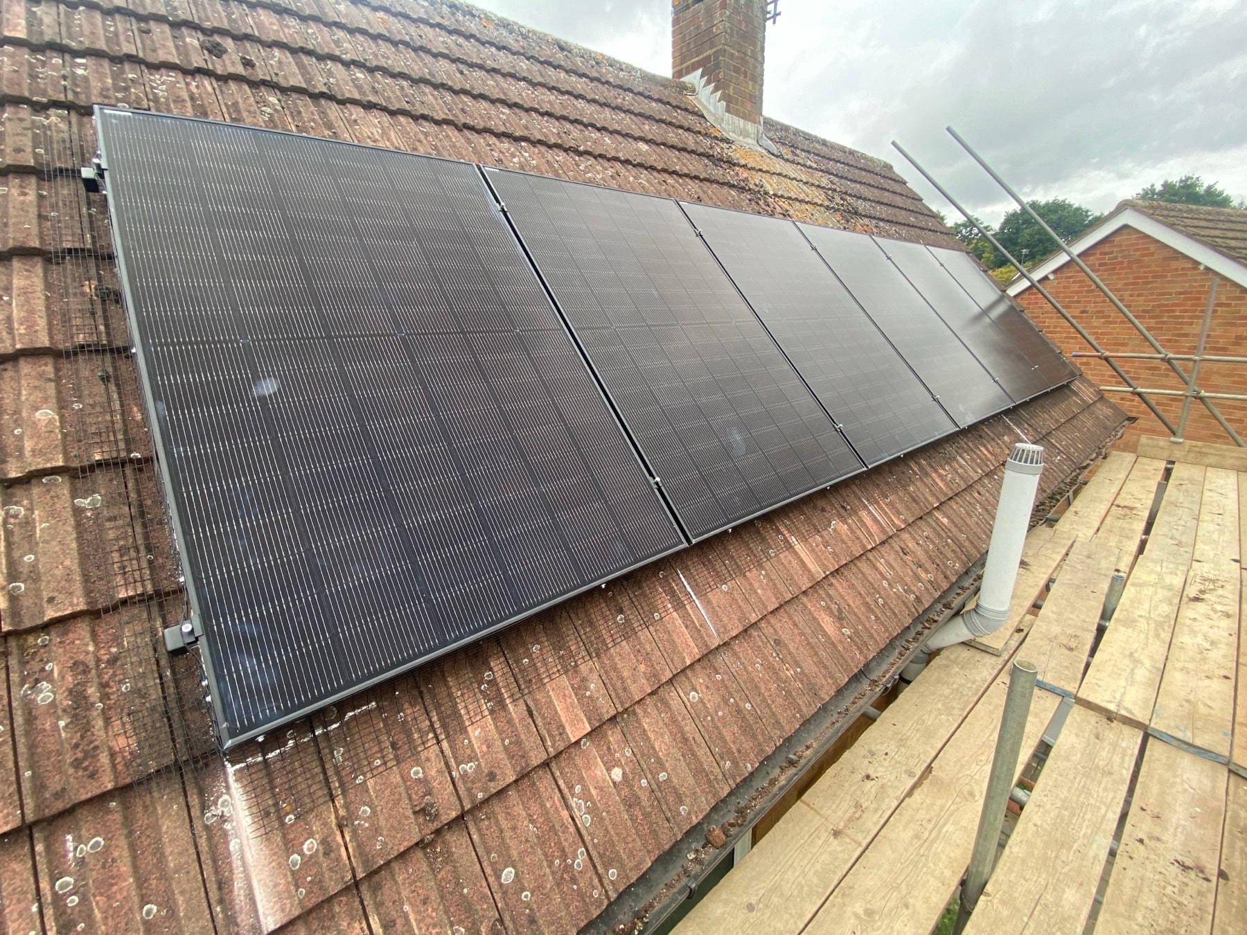 Black solar panels neatly installed across a red tiled roof