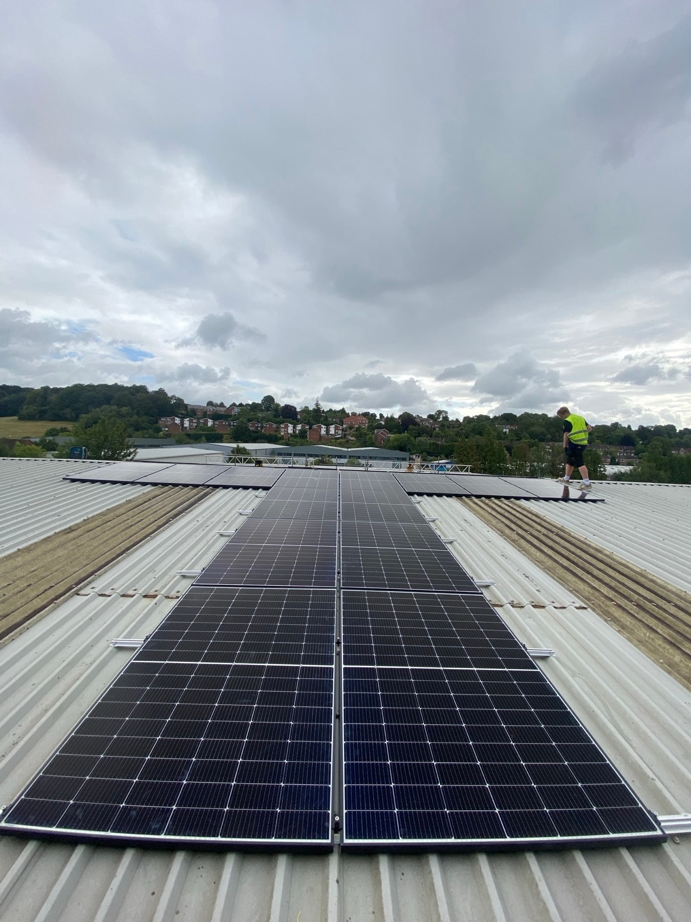Installer fitting solar panels on a large commercial metal roof