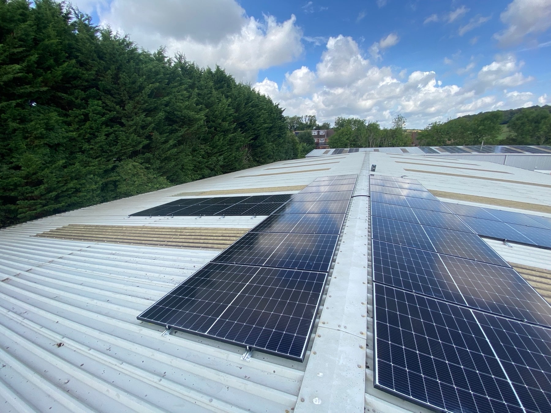 Commercial solar array on an industrial roof backed by trees
