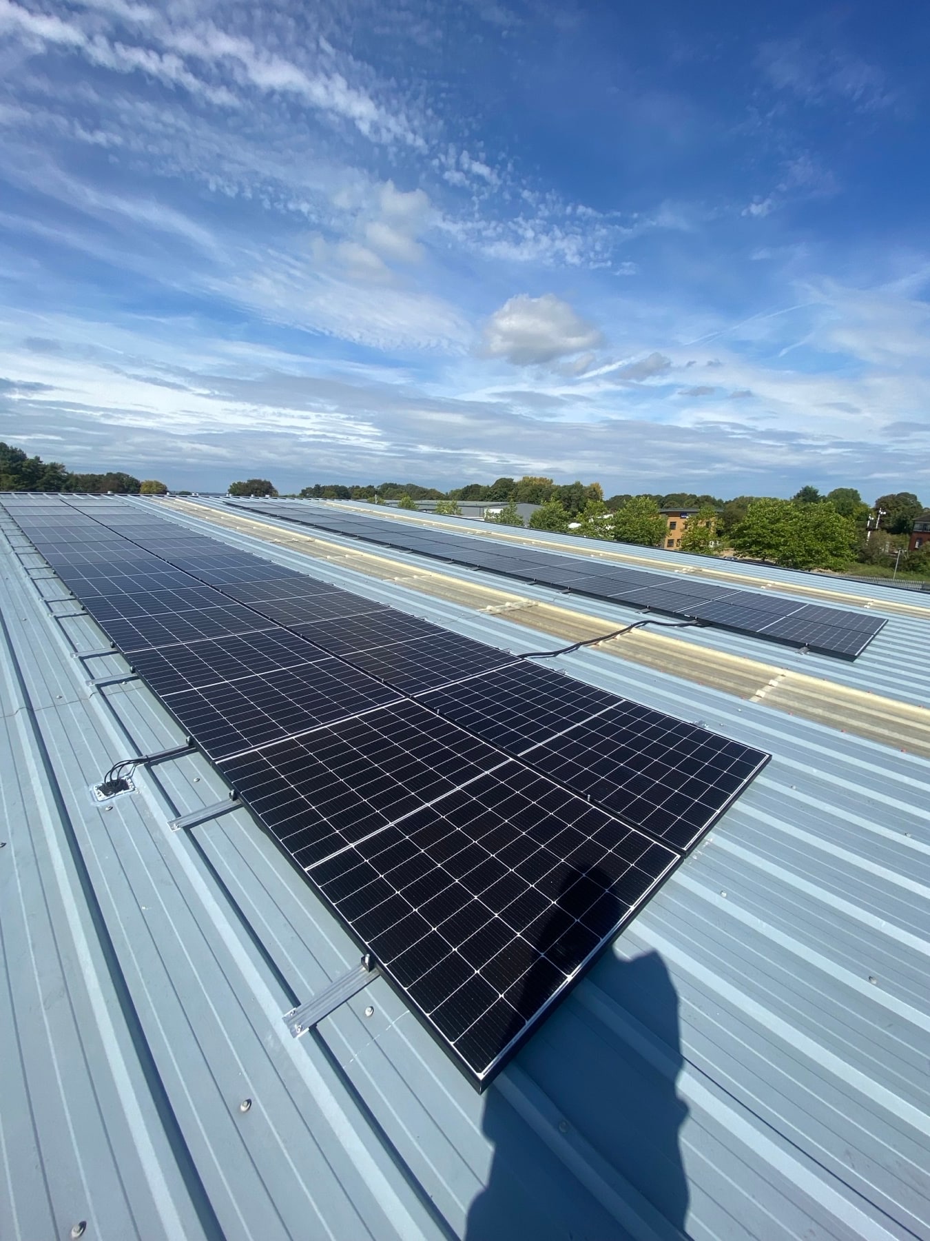 Commercial solar panels on a metal roof beneath a bright blue sky