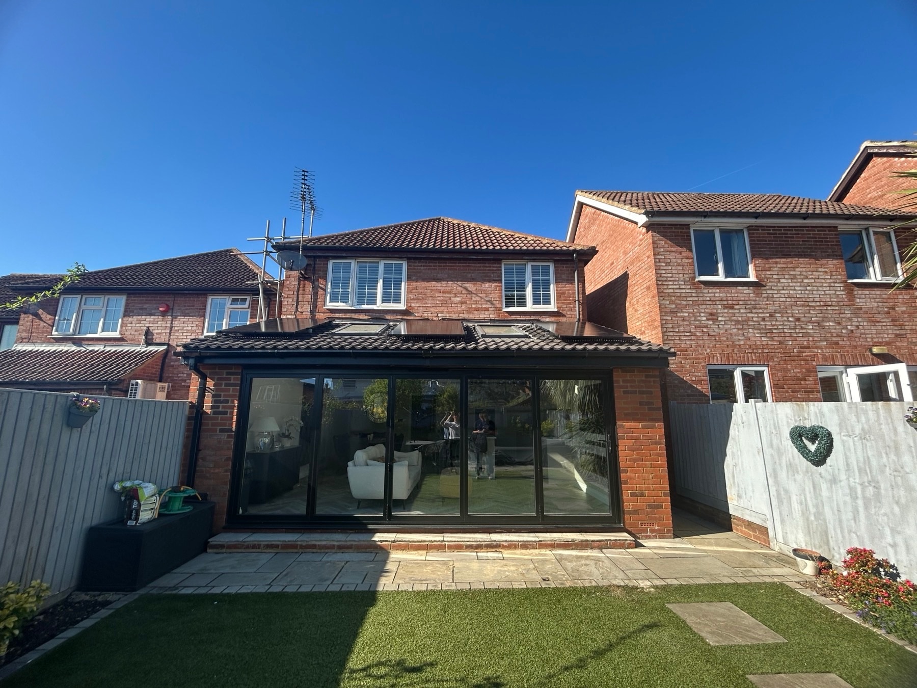Completed residential solar installation on a modern brick home extension against a clear blue sky